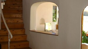 Una escalera de madera que conduce a un rellano con una pared blanca y una ventana pequeña.