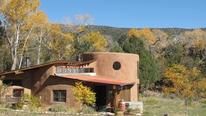 Un edificio rústico de adobe con techo plano y un amplio ventanal circular.