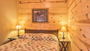 Una habitación con paneles de madera, una cama, dos mesitas de noche y un cuadro enmarcado en la pared.