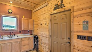 Un interior de madera con una zona de cocina, una puerta con un cartel y una ventana con vistas.