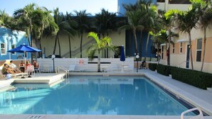 A swimming pool with a 3 FT depth marker, surrounded by palm trees and lounge chairs.