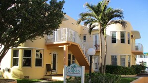 A two-story building with a yellow facade, a balcony, and a sign that reads "Oasis Surfside Condominium."