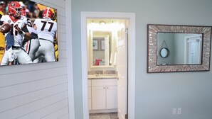 Un pasillo con una pared de recuerdos deportivos, un baño con espejo y una puerta que da a un dormitorio.