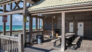 Una estructura de madera frente a la playa con mesas de picnic, una pizarra y baños.