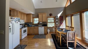 A modern kitchen with wooden cabinets, a dining area with a table and chairs, and large windows allowing natural light. - Heron Landing:  Escape to Lake Mayo.
Private cove, where nature abounds! 



 (Roxboro)