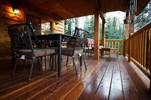 A wooden deck with a table and chairs, surrounded by a wooden railing.