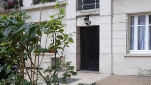 A multi-story building with balconies, a black door, and a small garden area with plants. - Luxury stay with champagne in an Artist's Atelier In The 5th (Paris)