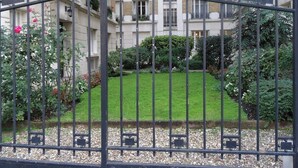 A gated courtyard with a well-maintained lawn, surrounded by multi-story residential buildings. - Luxury stay with champagne in an Artist's Atelier In The 5th (Paris)
