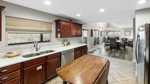 A modern kitchen with wooden cabinets, a large island, and a dining area with a chandelier. - GREAT view DOWNTOWN Gatlinburg with views,community pool, hot tub and fireplace (Gatlinburg)