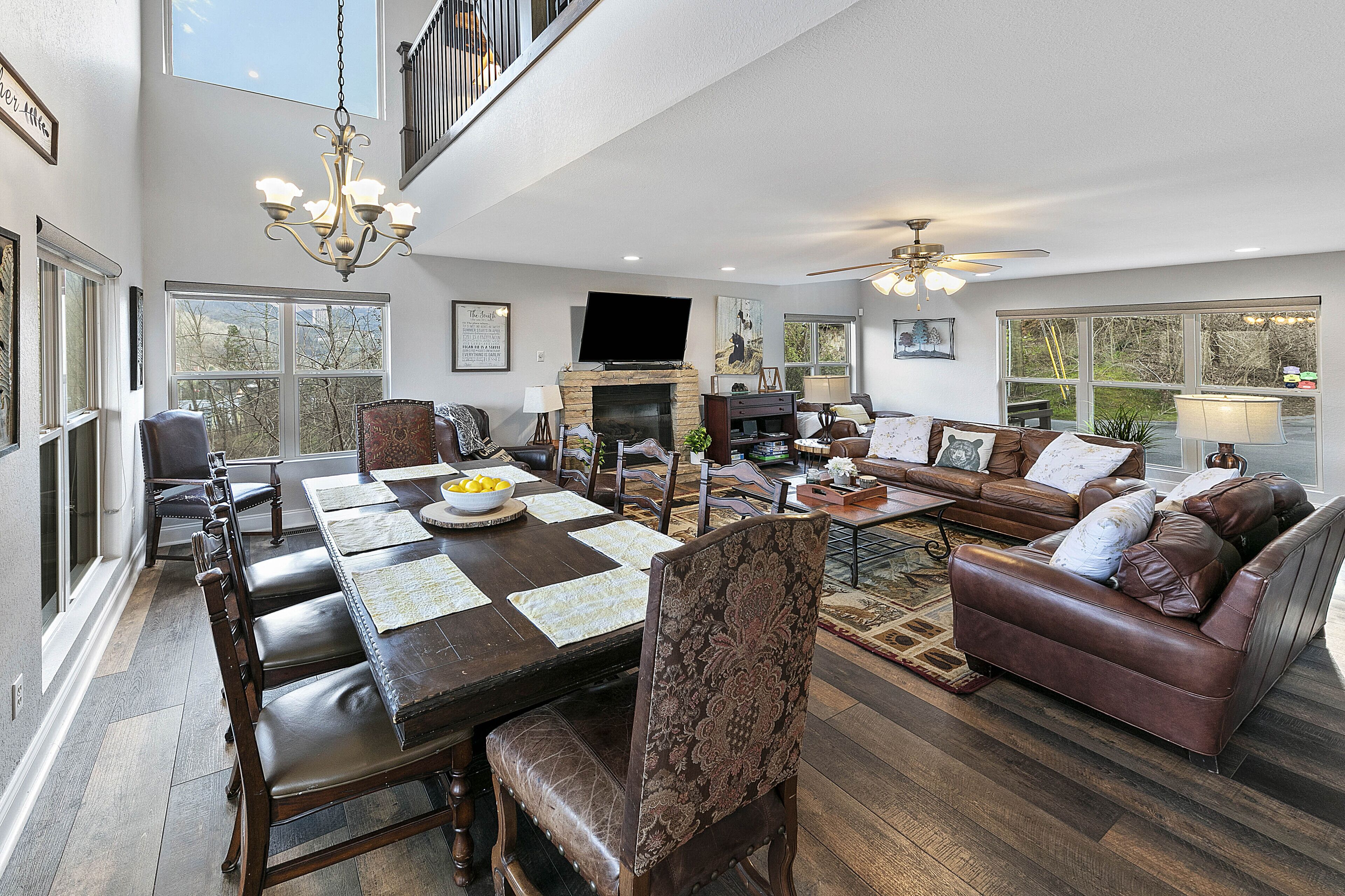 A spacious living room with a large dining table, leather sofas, and a fireplace.