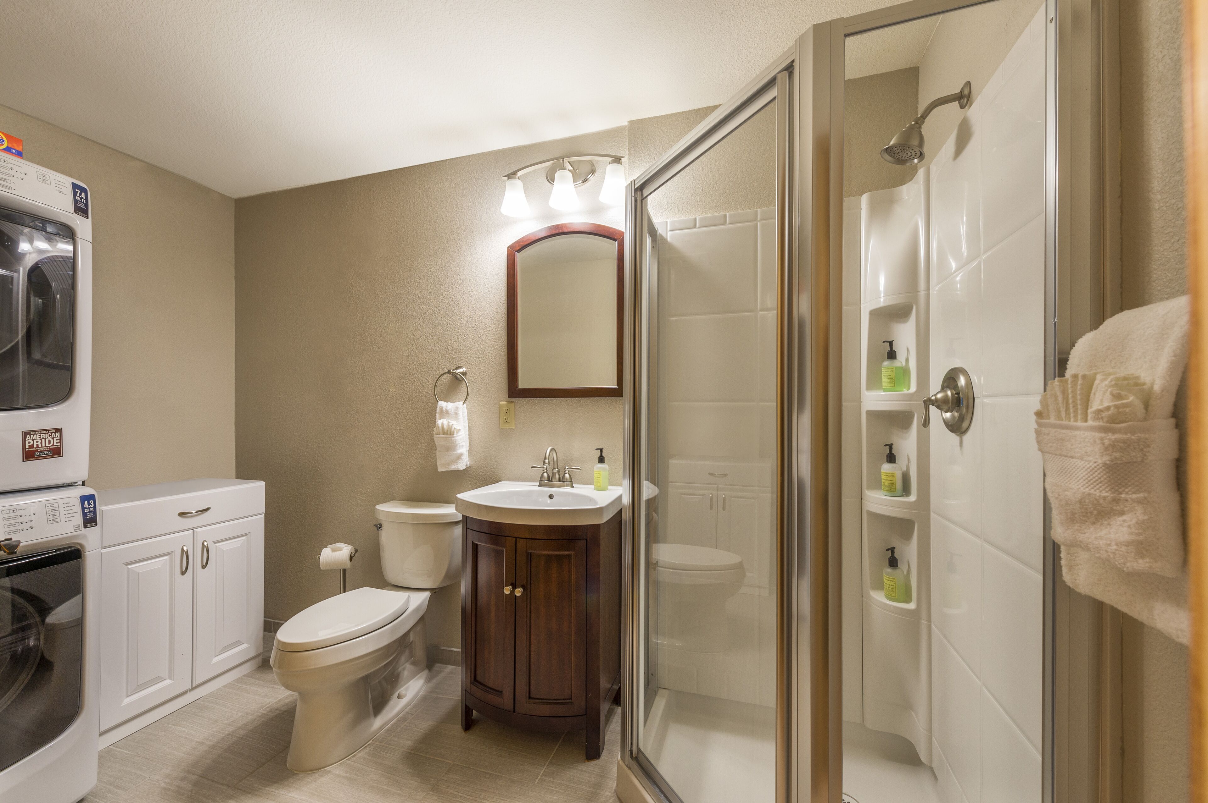 Ein Badezimmer mit Duschkabine, Toilette, Waschbecken und Waschmaschine.