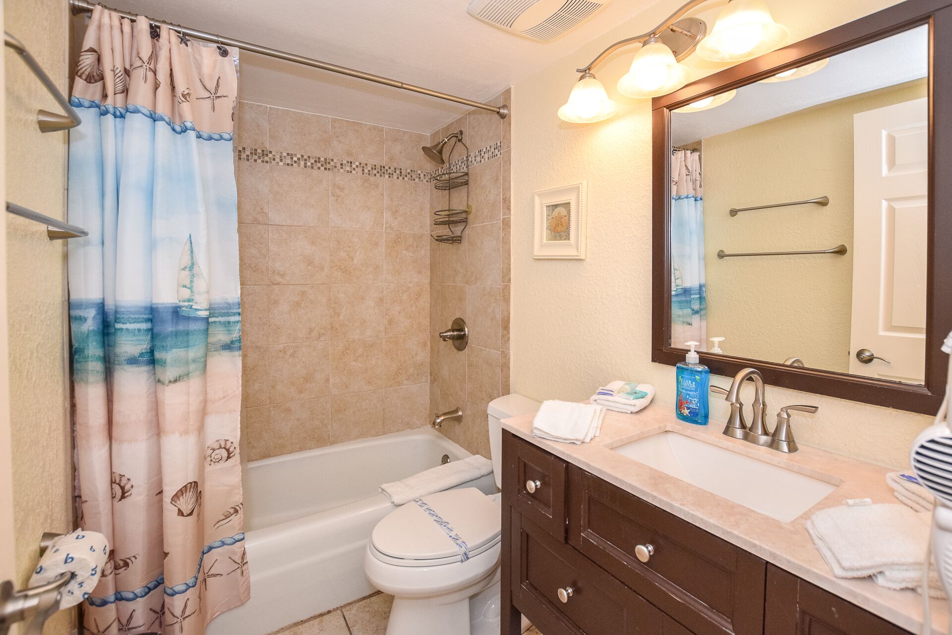 Un baño con bañera, inodoro, lavamanos y un espejo grande.