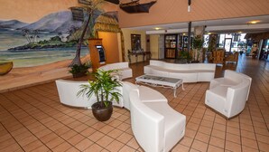 A spacious lobby with white sofas, a coffee table, and a large potted plant.
