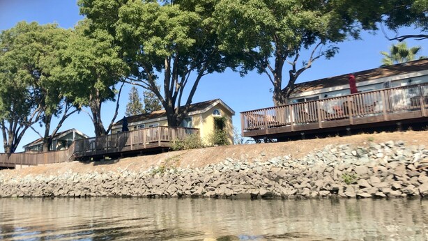 A riverside property with wooden walkways and a stone retaining wall.