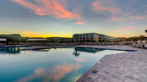 A swimming pool with lounge chairs and a building in the background.