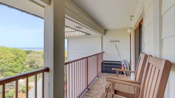 Enjoy the serene view from this balcony with a seating area and table.
