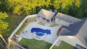 Vue aérienne d’une propriété résidentielle dotée d’une piscine, d’un patio couvert et d’un garage.