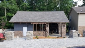 Une maison avec une façade en pierre, une terrasse carrelée et une piscine.