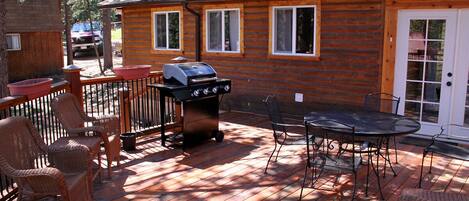 En stuga byggd av trä med en veranda, utomhusmöbler och en grill.