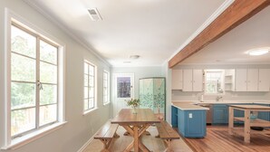 Una cocina amplia con una mesa de madera y bancos, ventanas grandes y vistas al exterior.