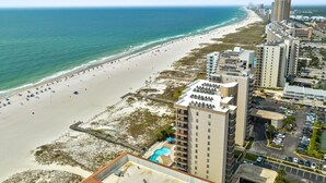 Ein Strandhotel mit Pool, Blick auf den Strand und angrenzenden Hochhäusern.