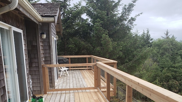 Um deck de madeira com guarda-corpo, uma porta e uma janela.