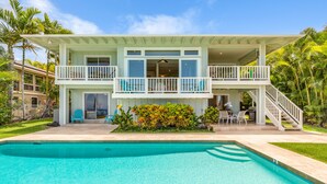 Ein zweistöckiges Haus mit Schwimmbad, Balkon und Treppe, die zu der oberen Etage führt.