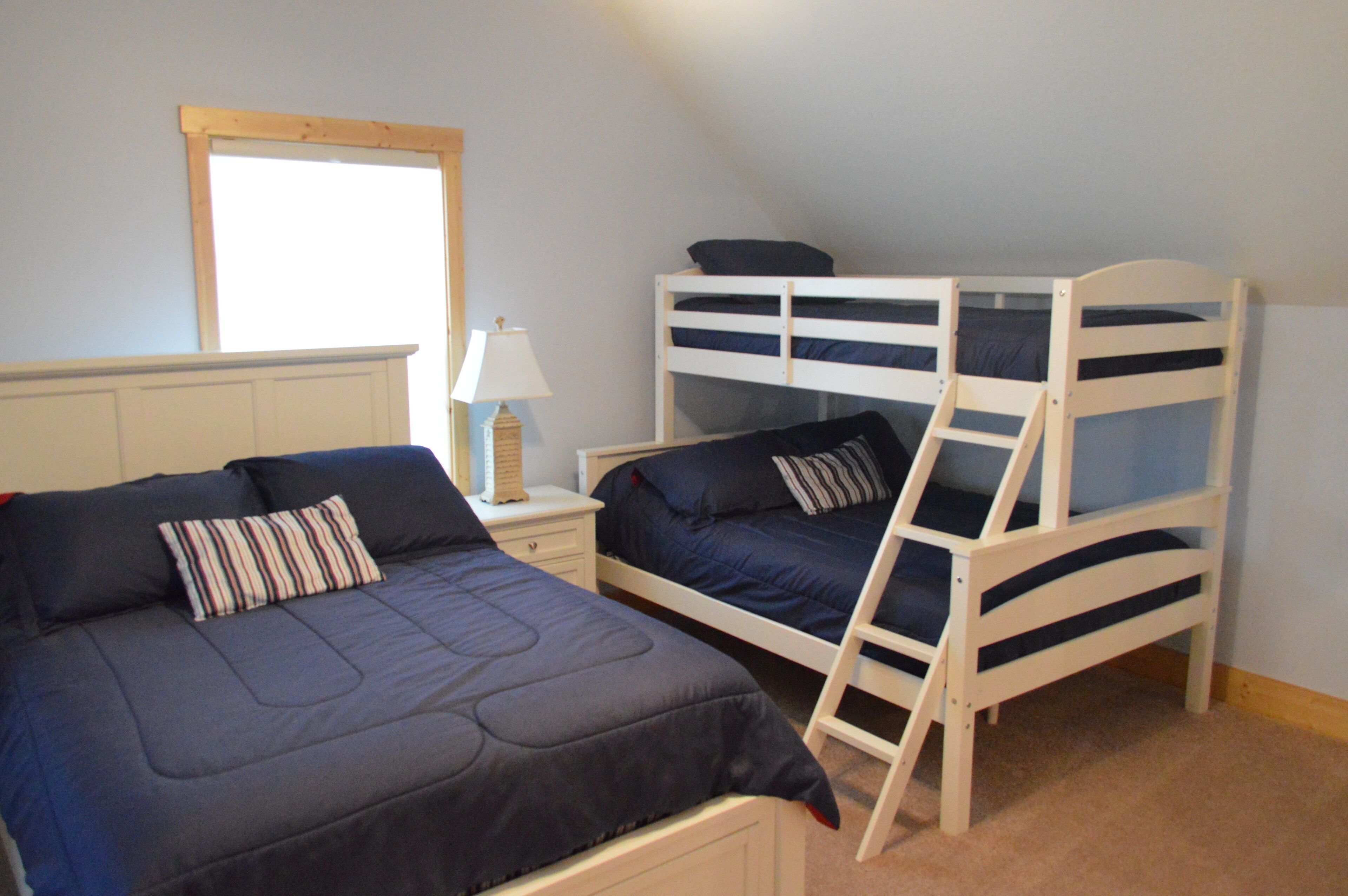 Una camera da letto con due letti a castello, un comodino con una lampada e una finestra.