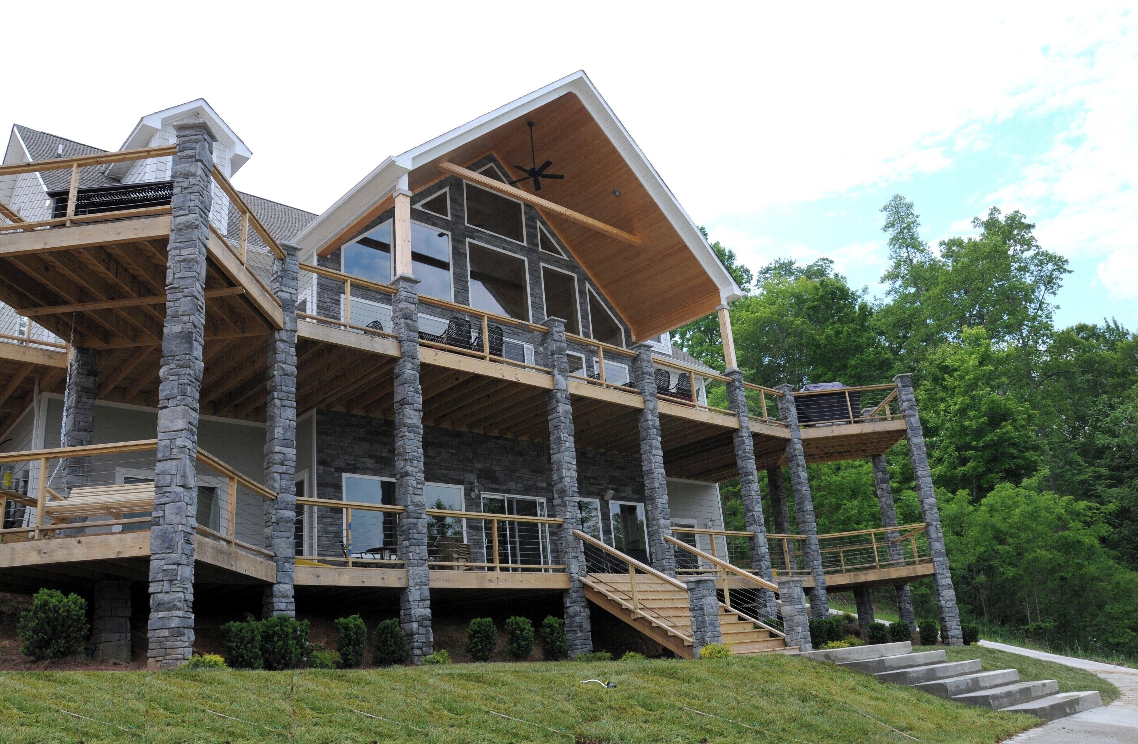 A multi-level stone and wood cabin with a balcony and staircase.