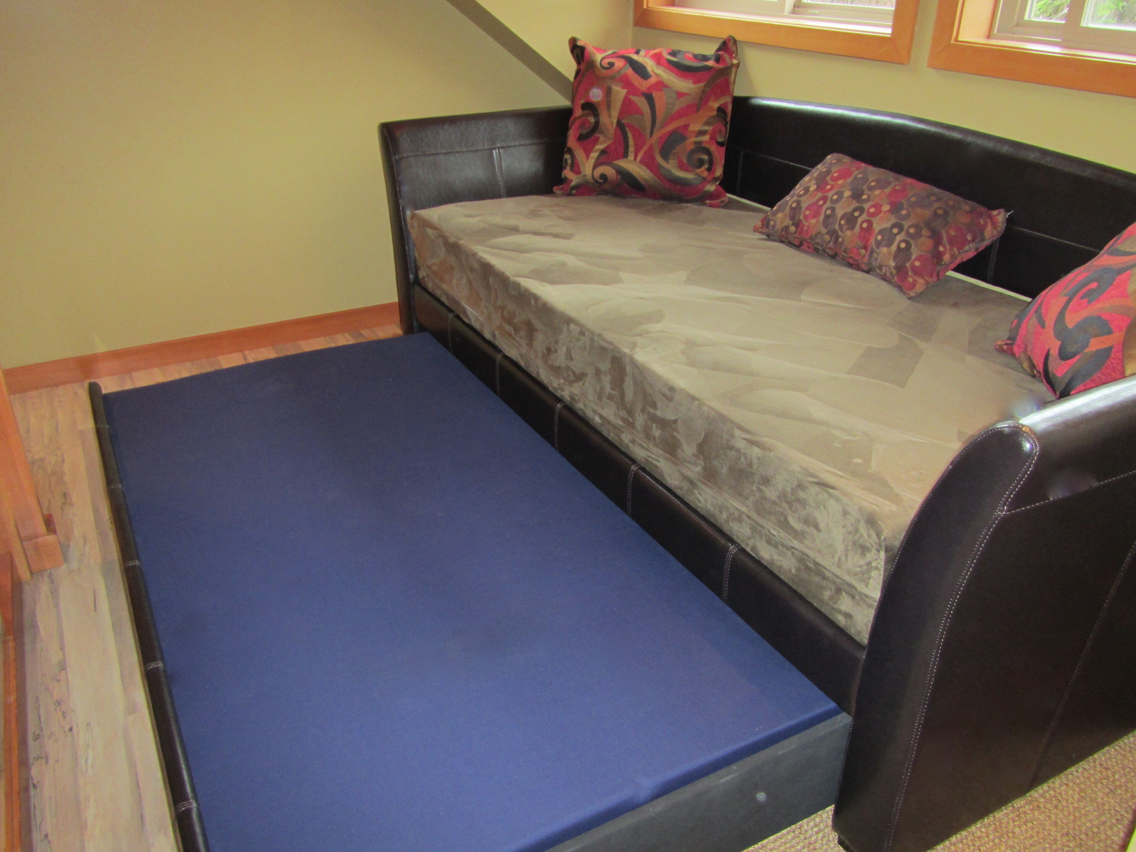 Una habitación pequeña con cama individual, colchón azul y cabecera negra.