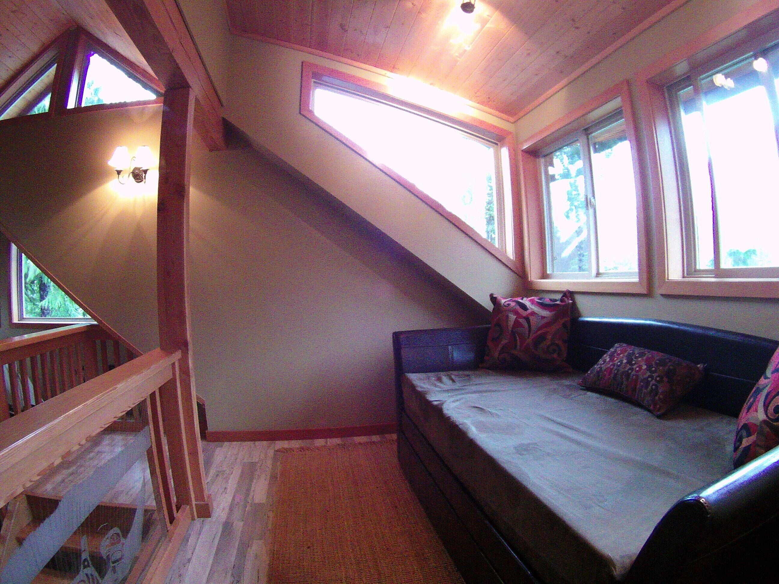Une pièce avec un lit, une fenêtre et un escalier.