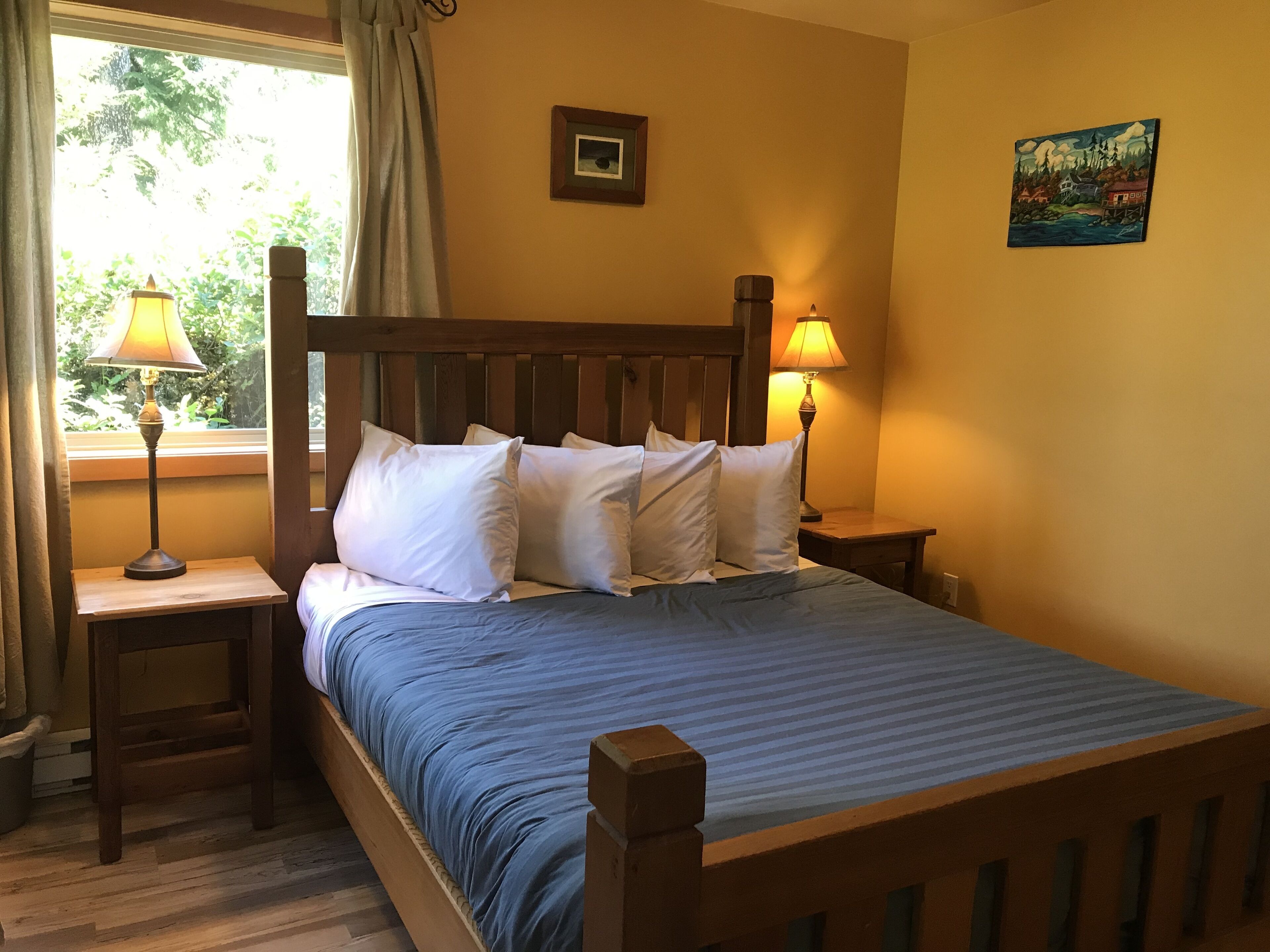 A neatly made bed with white pillows and a blue bedspread in a room with wooden headboard and nightstands.