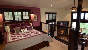 Une chambre avec un grand lit, une cheminée et un balcon doté d’une balustrade.