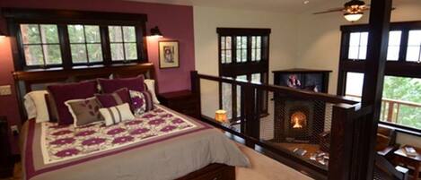 Un dormitorio con una cama grande, una chimenea y un balcón con barandilla.