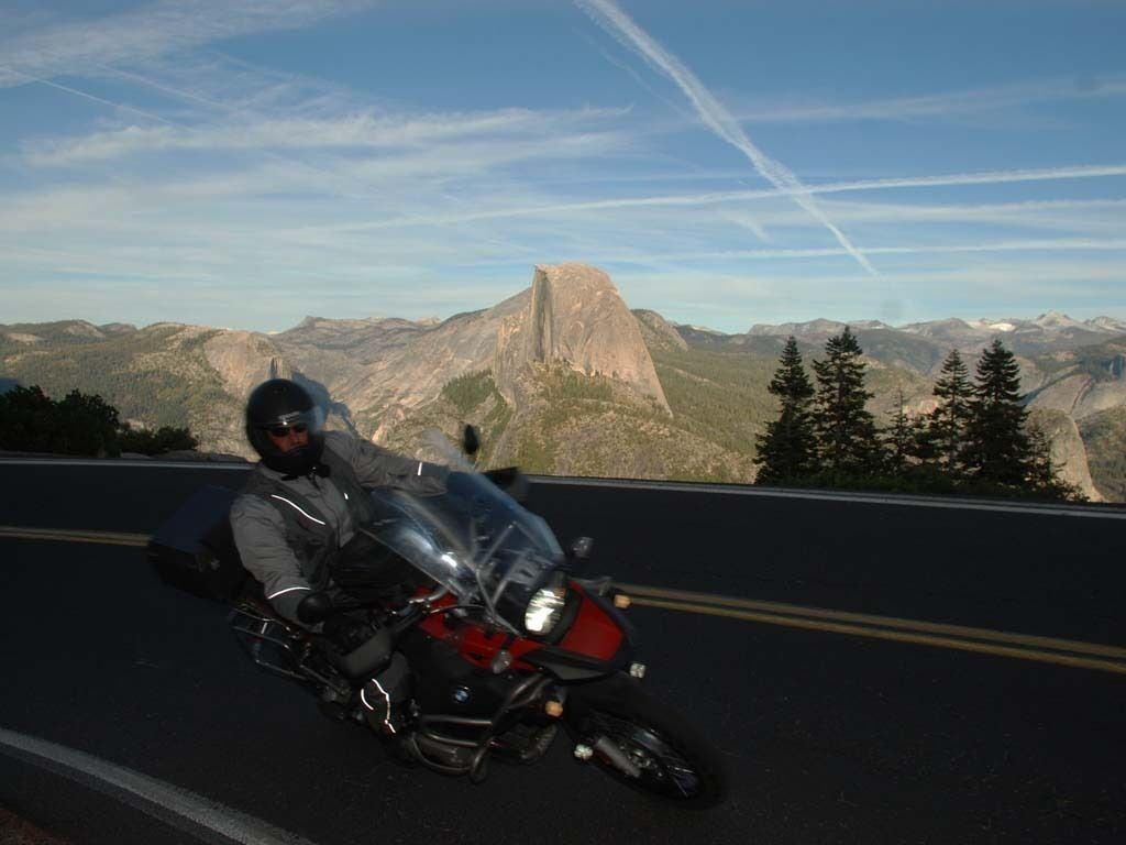 Una persona conduciendo una motocicleta por una carretera, con vistas a una montaña al fondo.
