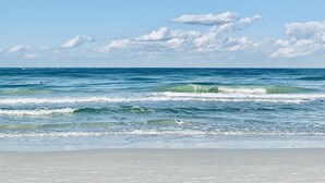 Ein Strand mit Wellen, einem klaren Himmel und einem Boot in der Ferne.