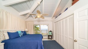 Un dormitorio con cama, ventilador de techo, vista al exterior y puerta a un armario.