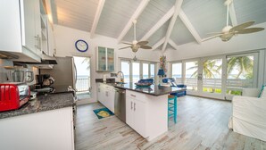 Una cocina amplia con una isla grande, armarios blancos y vista al océano.
