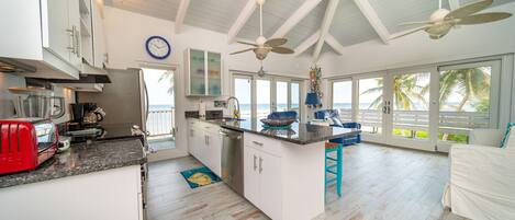 A spacious kitchen with a large island, white cabinetry, and a view of the ocean.