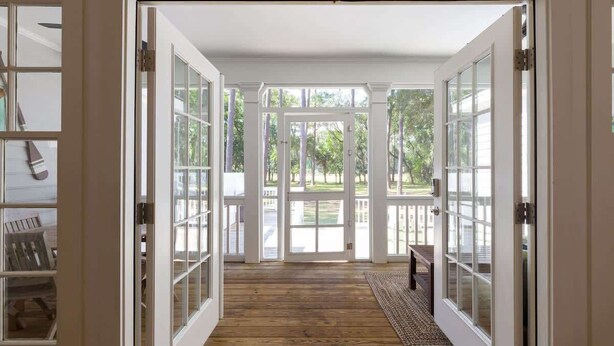 A spacious entryway with a wooden floor leading to a deck area.