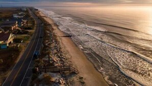 A coastal road with a beach on one side and buildings on the other. - Beach Front Folly Beach 6 Bedroom 7 Bathroom Sleeps 14 (Folly Beach)