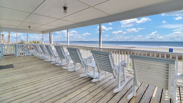 A covered deck with white rocking chairs facing a beach view. - Beach Front Folly Beach 6 Bedroom 7 Bathroom Sleeps 14 (Folly Beach)