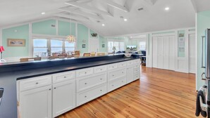 A spacious kitchen with a large island, white cabinetry, and wooden flooring. - Beach Front Folly Beach 6 Bedroom 7 Bathroom Sleeps 14 (Folly Beach)