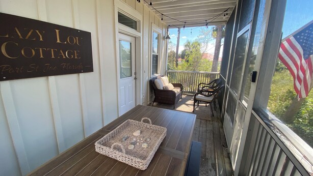 A porch with a sign reading "Lazy Lou Cottage Part St. Joe, Florida". - LazyLou:Low Rates for Fall:4 Bedroom+4.5 Bath+3Pools+Hot Tub+Screen Porches (Port St Joe)