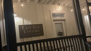 A rustic interior with exposed wooden beams, a sign reading "Lazy Lou Cottage Port St. John, Florida," and a black metal railing. - LazyLou:Low Rates for Fall:4 Bedroom+4.5 Bath+3Pools+Hot Tub+Screen Porches (Port St Joe)