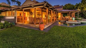 A modern house with a pool, wooden deck, and a dining area.