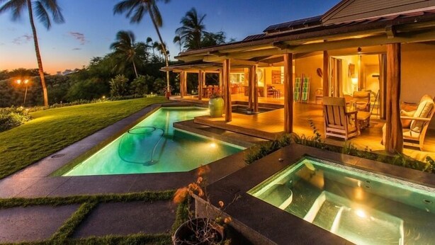 A modern house with a swimming pool, outdoor seating area, and a well-maintained lawn.
