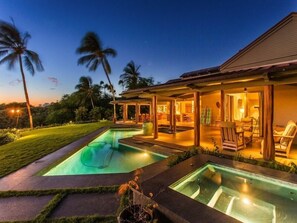 Una casa moderna con piscina, zona de estar exterior y césped bien cuidado.