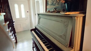 Un grand piano dans un vaste hall, avec un grand tableau accroché au-dessus.