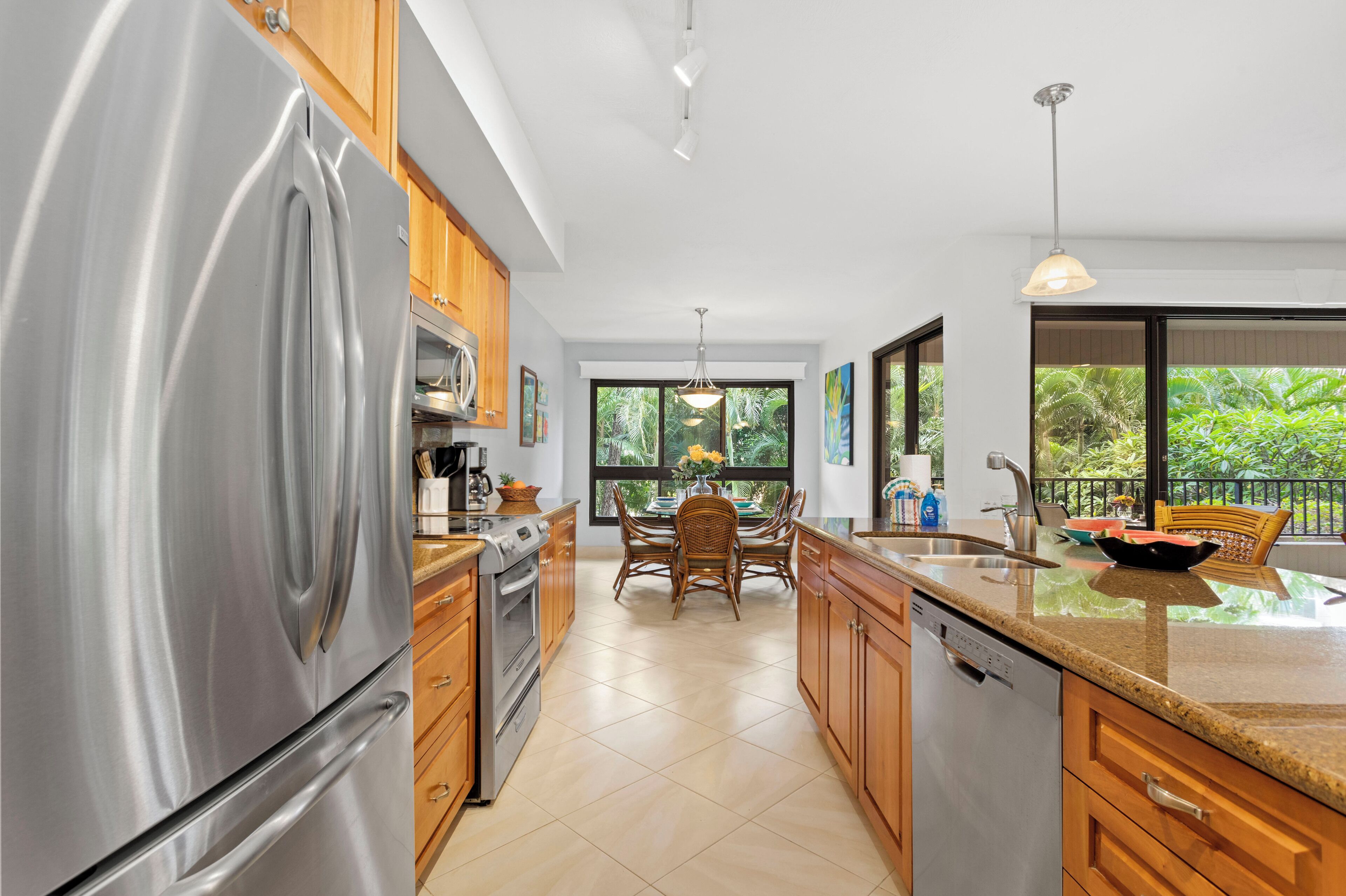 Una cocina moderna con electrodomésticos de acero inoxidable, armarios de madera y un comedor con vistas a zonas verdes.